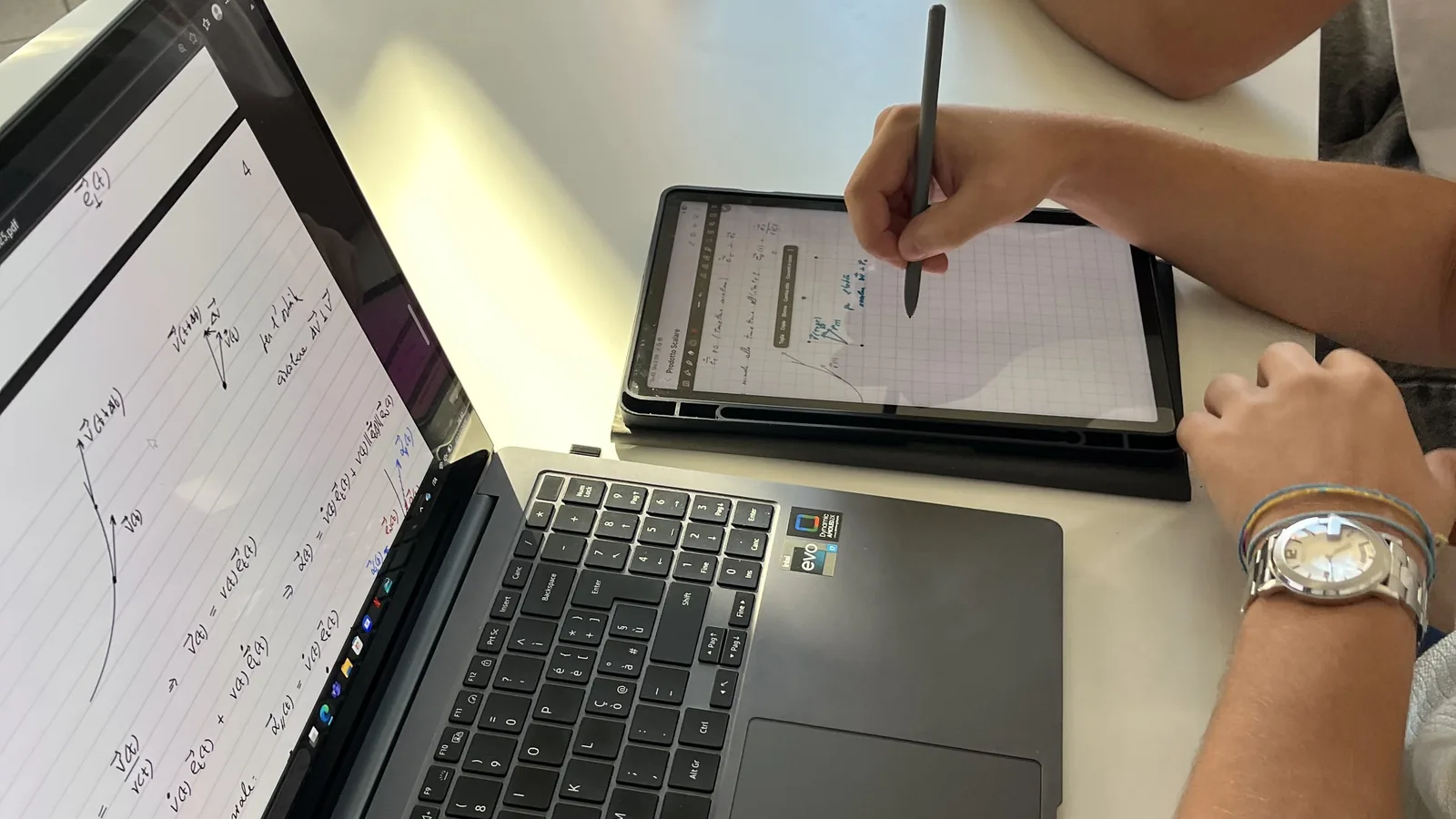 Un portatile e un tablet aperti sul banco accanto a un quaderno, durante una lezione